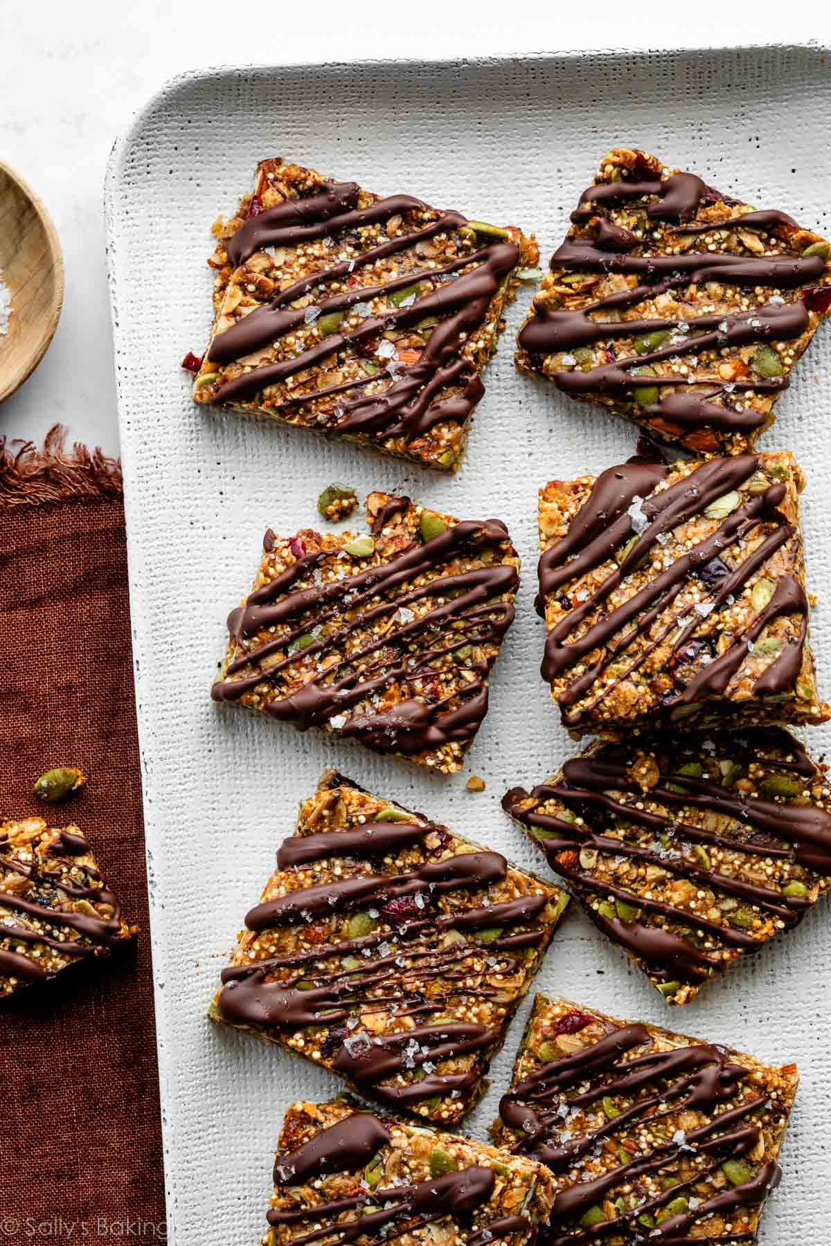 quinoa bars with dark chocolate drizzle on white tray.