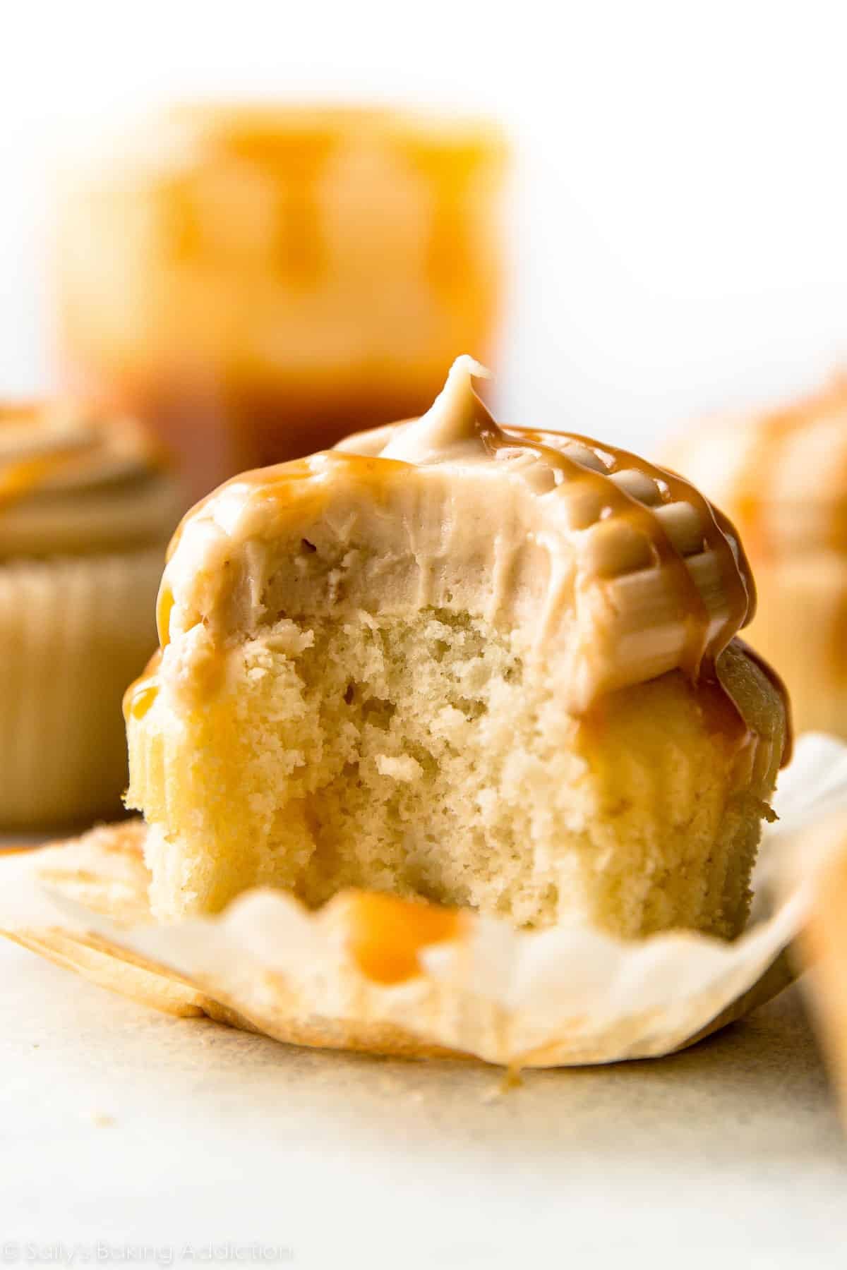 salted caramel frosting and caramel sauce on vanilla cupcake with bite taken out.