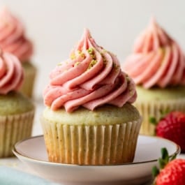 pistachio cupcake with strawberry buttercream piped on top.