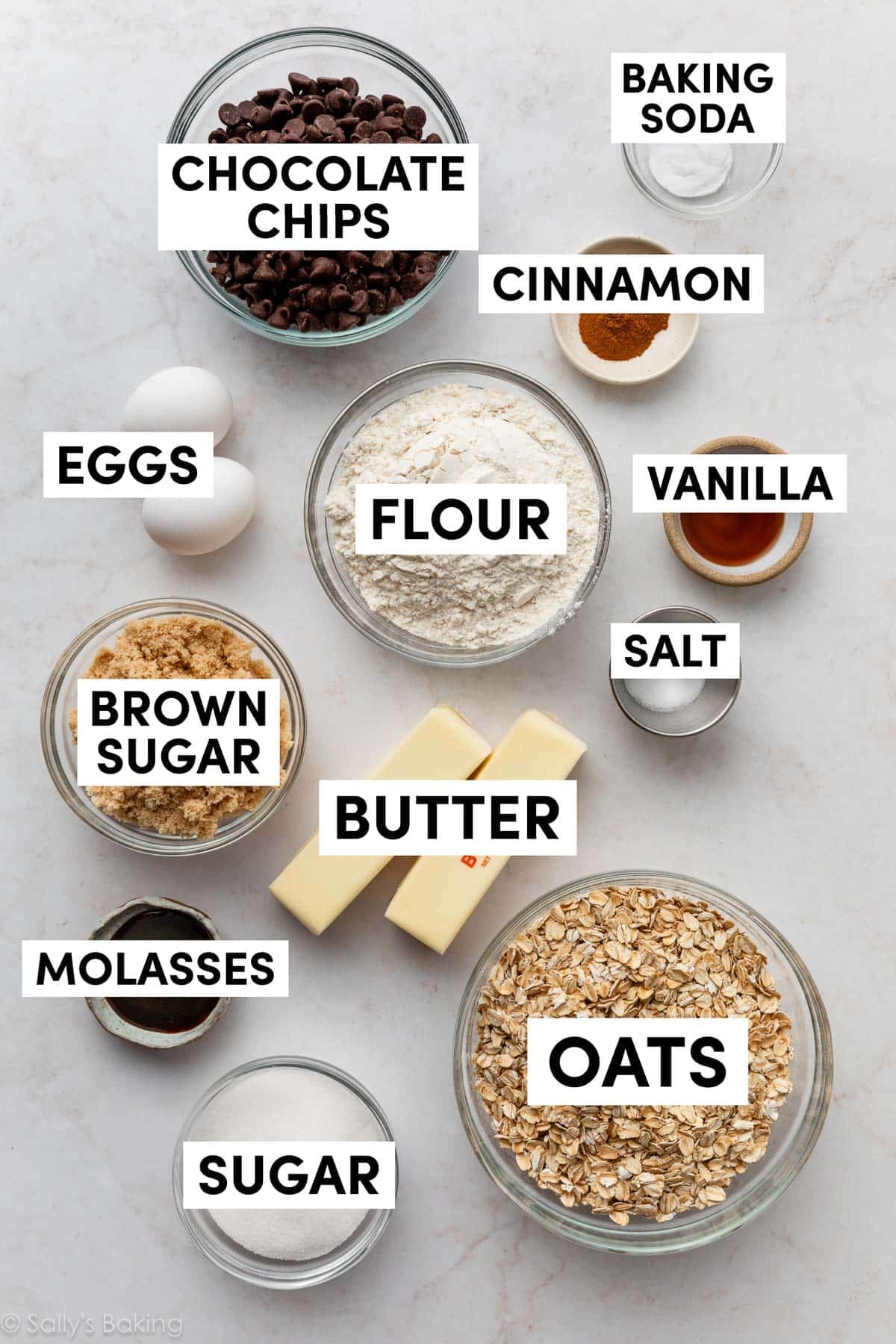 ingredients on marble surface including oats, flour, vanilla, butter, brown sugar, eggs, cinnamon, and molasses.