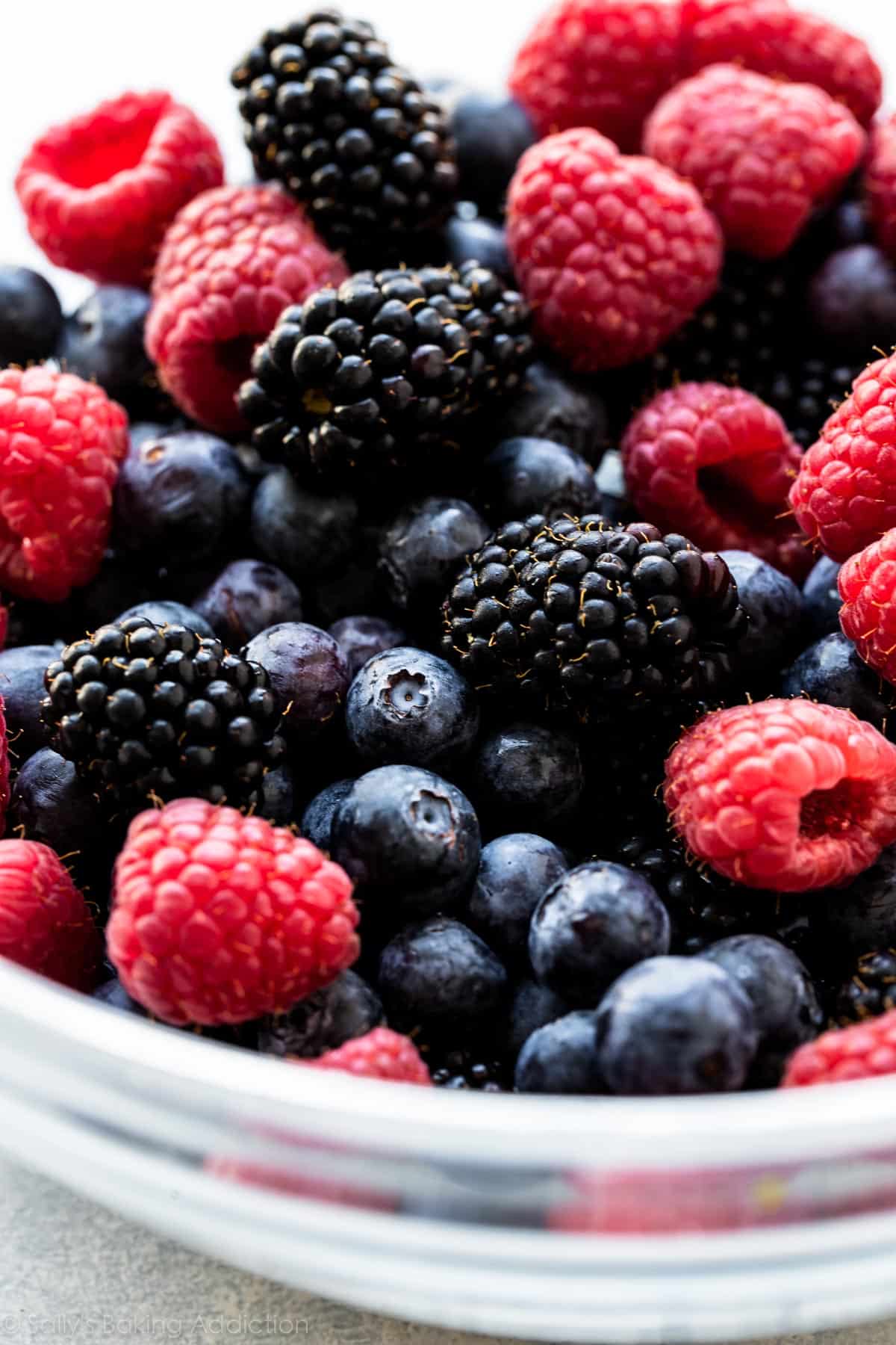blueberries, raspberries, and blackberries in a glass bowl