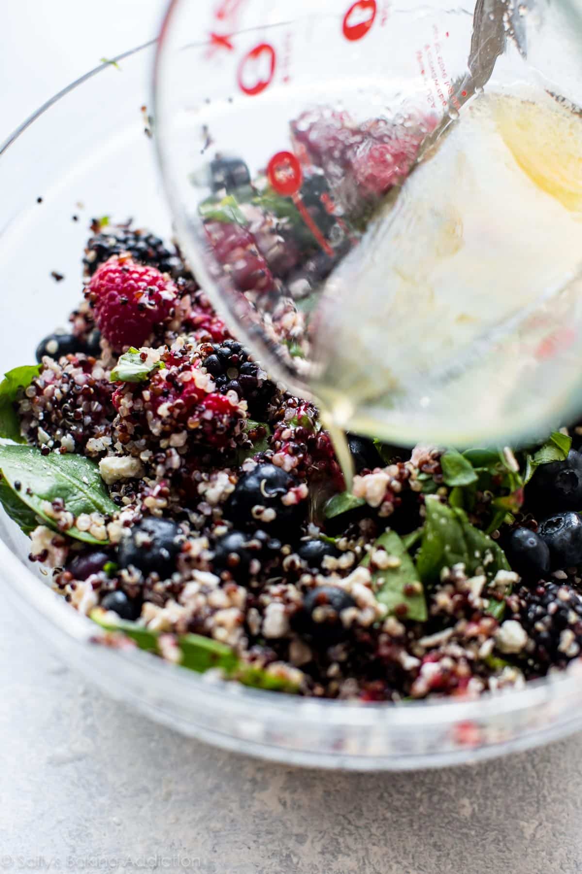 pouring dressing onto salad in a glass bowl