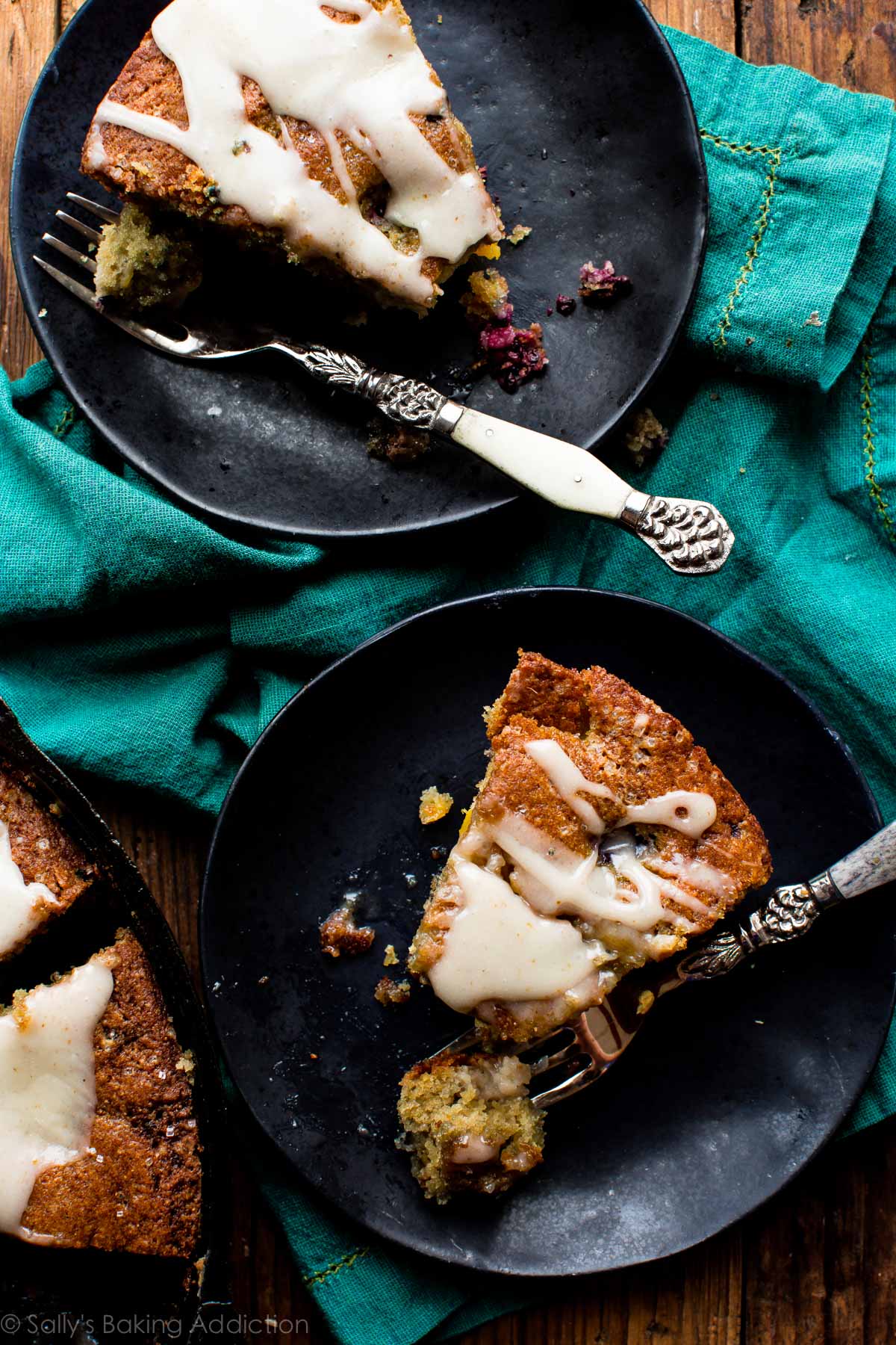 slices of blackberry peach skillet cornmeal cake on black plates with forks
