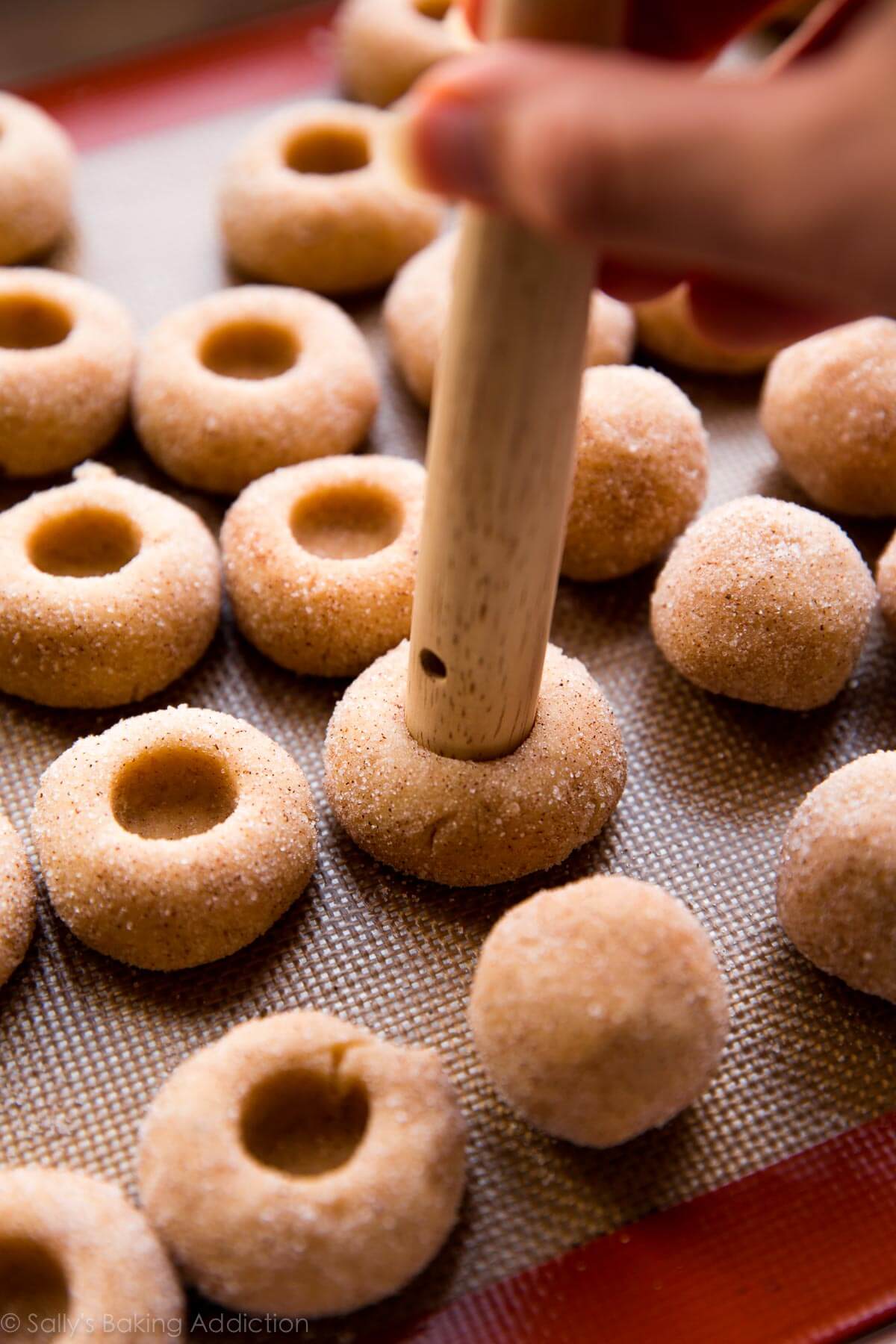 using the end of a wooden spatula to make indents in cookie dough balls