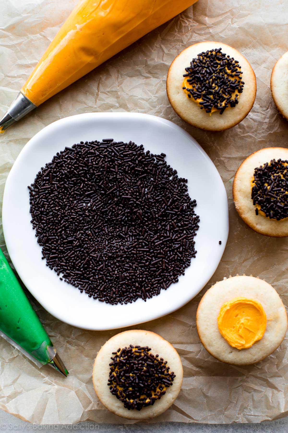 toppings for sunflower cupcakes including chocolate sprinkles on a plate and yellow and green frosting in piping bags