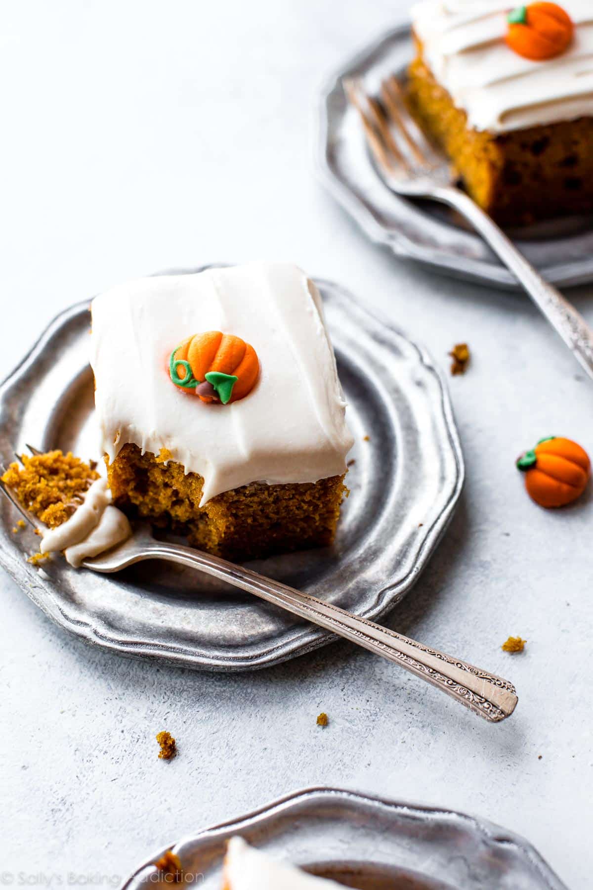 slices of pumpkin cake with cream cheese frosting on silver plates with forks