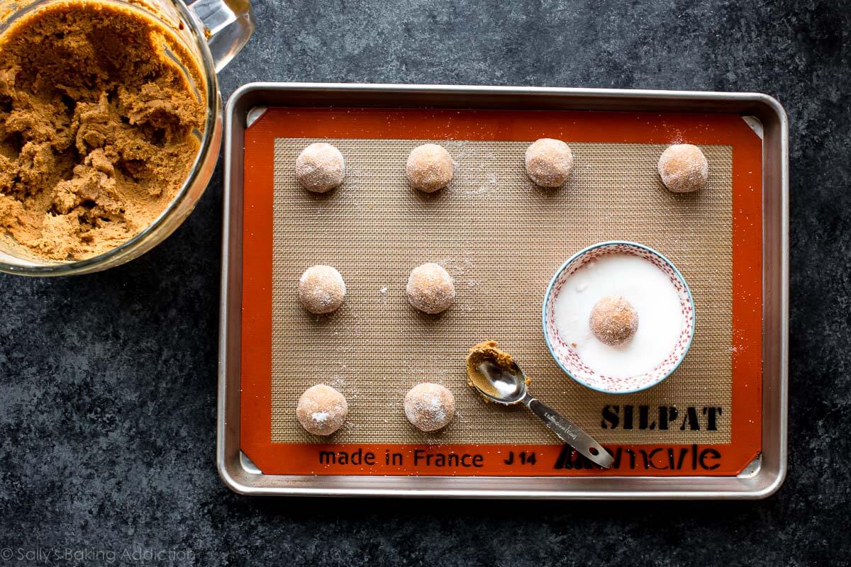 molasses cookie dough balls rolled in granulated sugar on a baking sheet