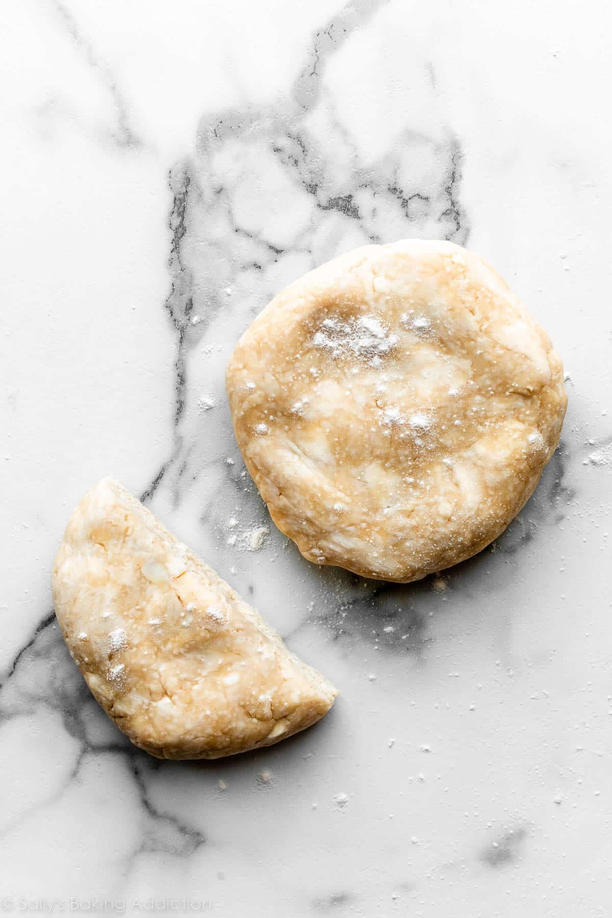 one and 1/2 pie dough discs on lightly floured marble counter.