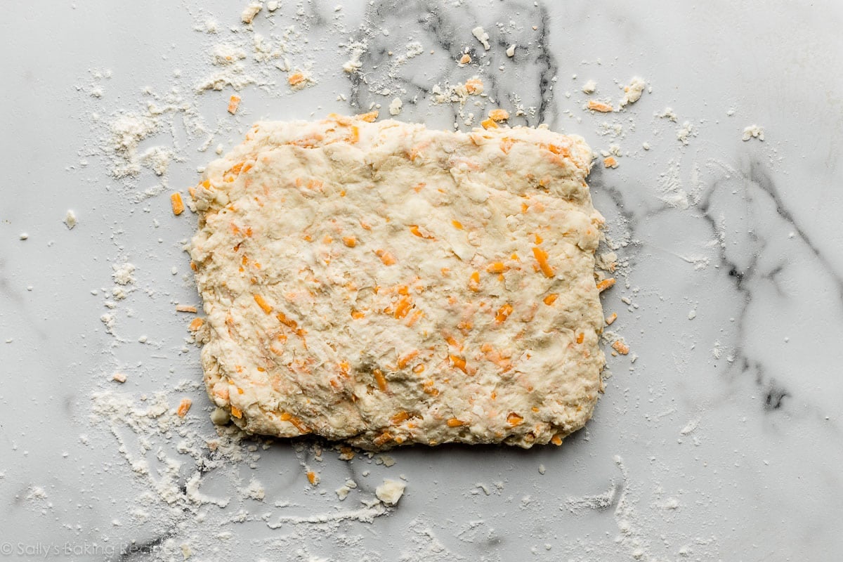 cheddar cheese filled dough in rectangle shape on marble counter.