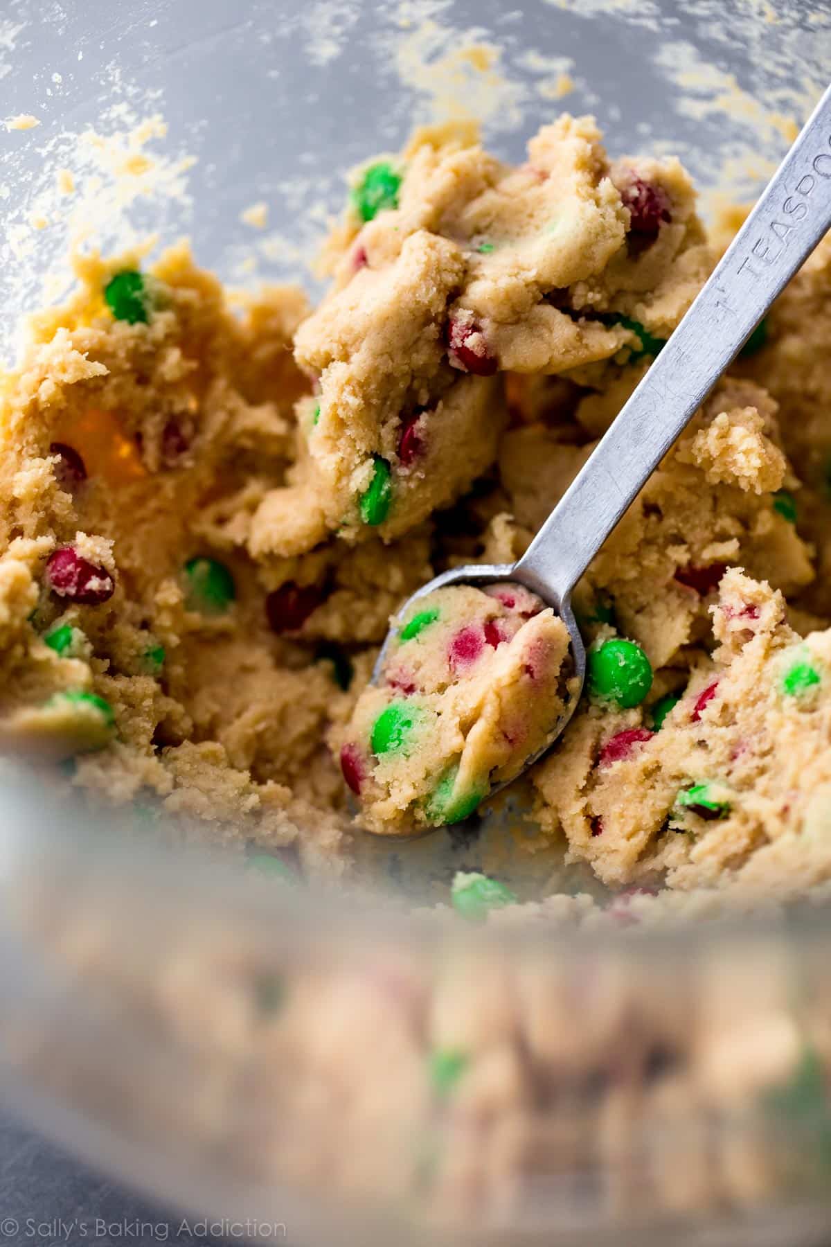 mini M&M cookie dough in a glass bowl with a teaspoon
