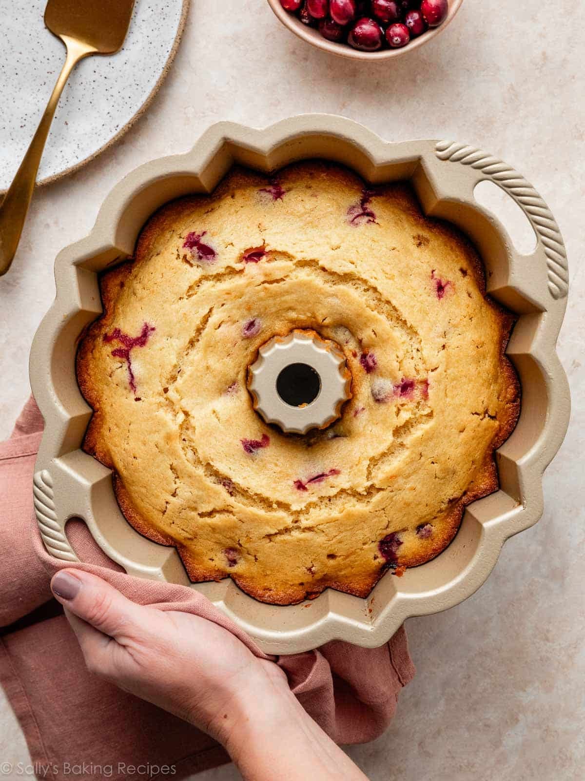 hand holding gold Bundt cake pan with cranberry cake.