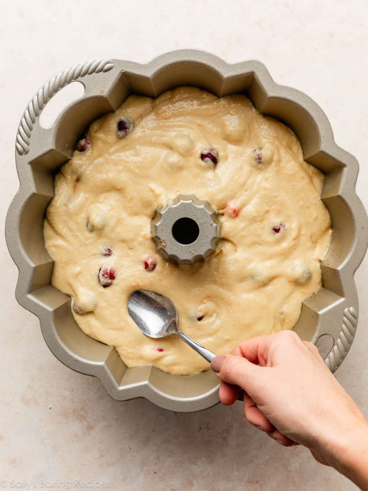 spoon spreading batter in gold Bundt pan.