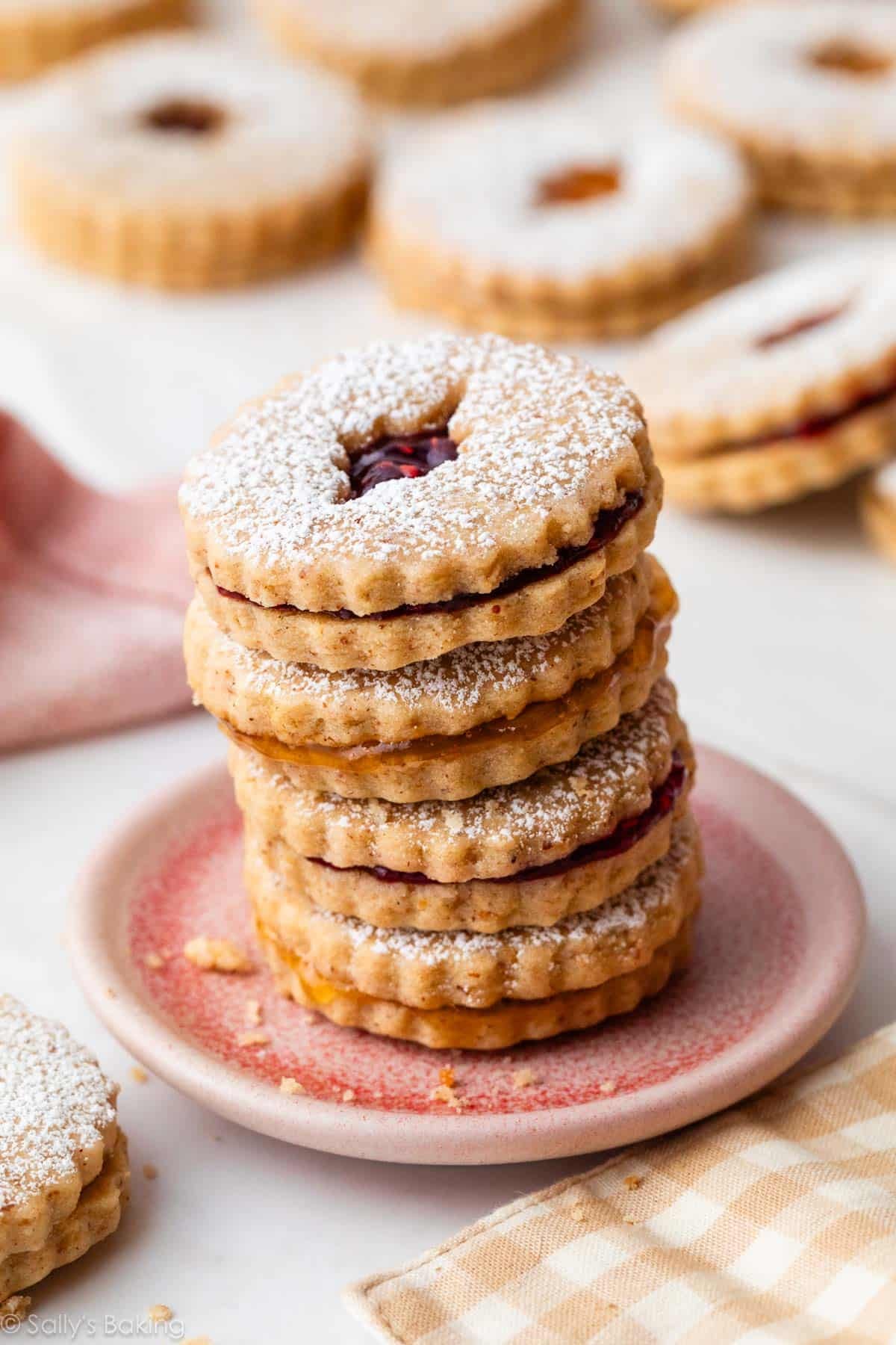 stack of linzer cookies on small pink plate.