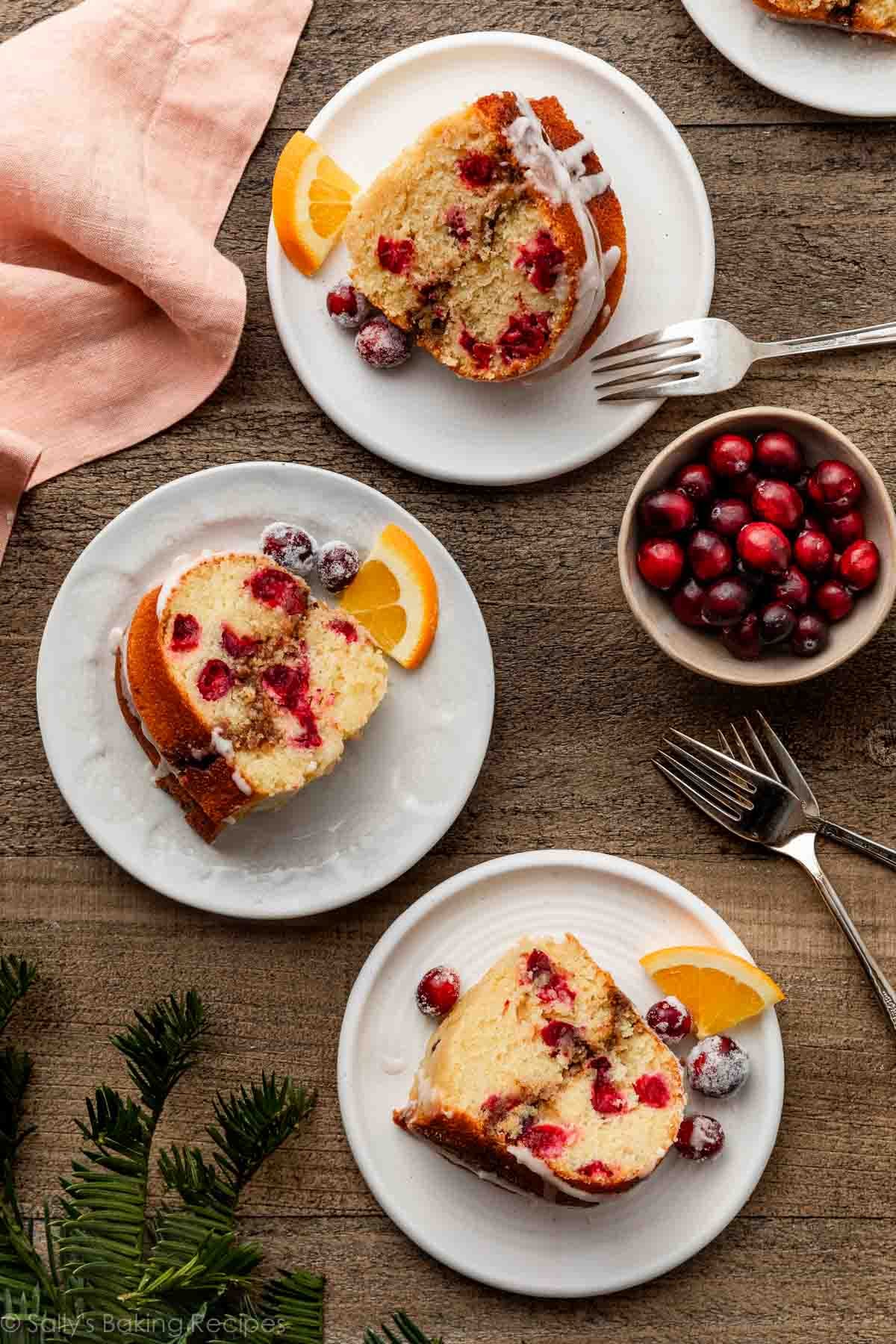 overhead photo of cranberry orange bundt cake slices with bowl of cranberries and pink linen next to them.