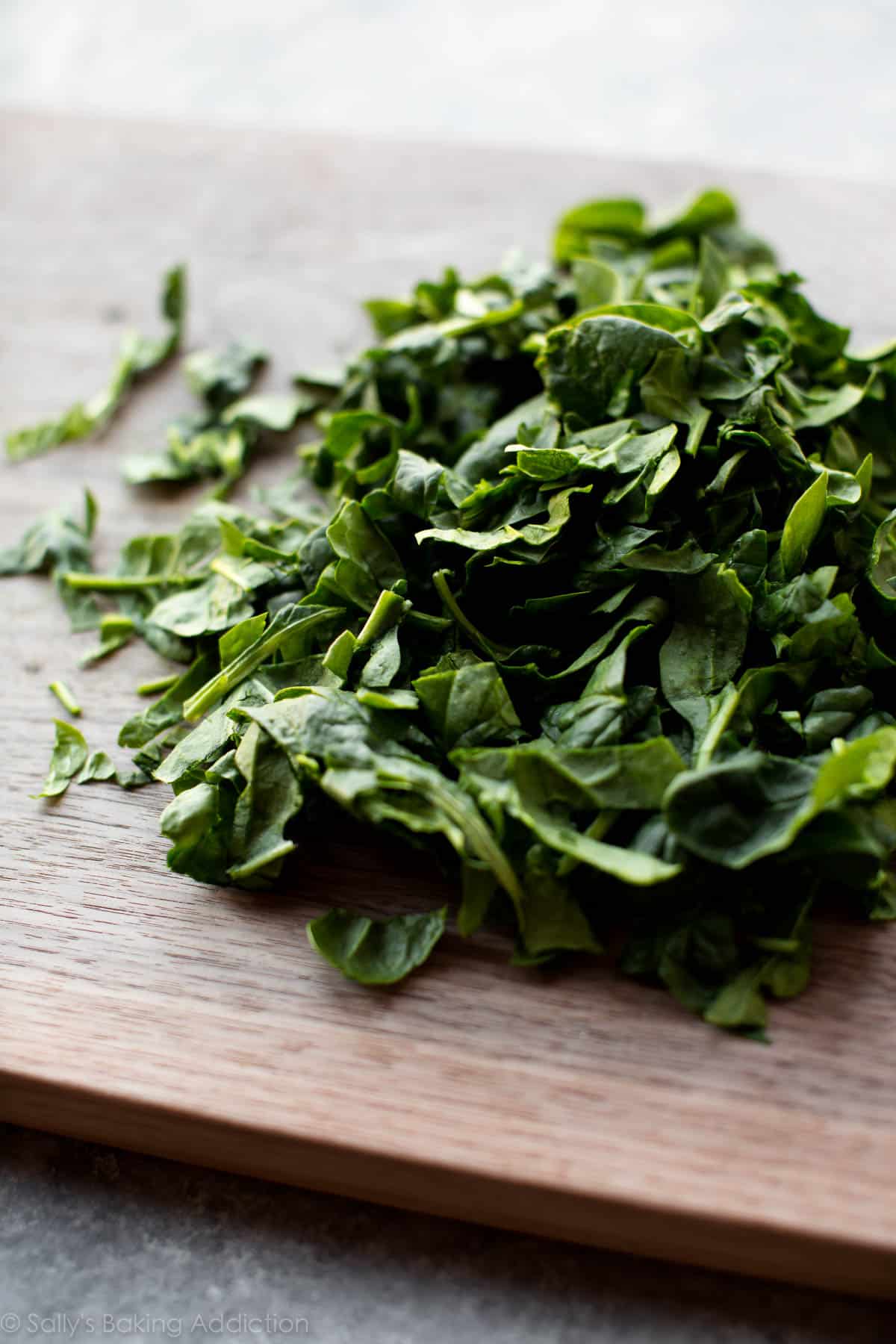 fresh spinach on a wood cutting board.