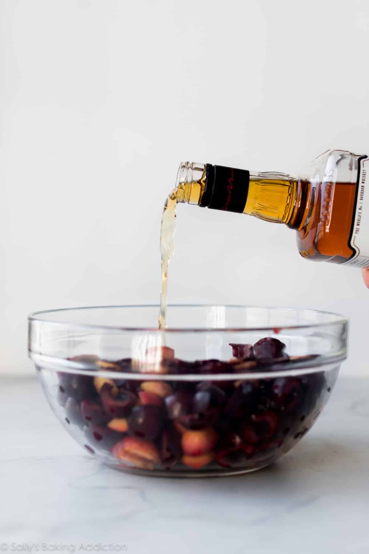 pouring bourbon into cherry crisp filling