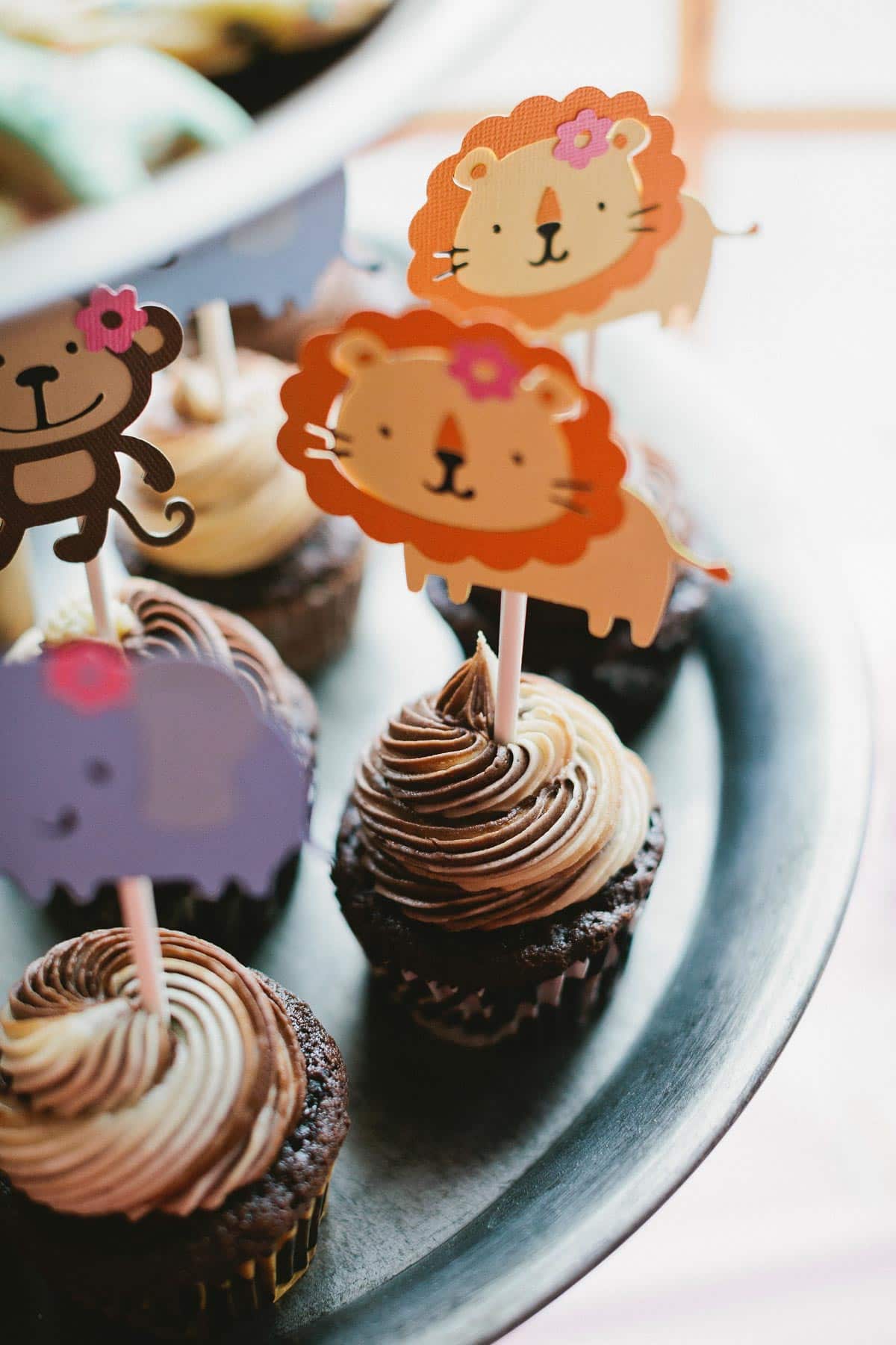 cupcakes on a dessert stand with safari cupcake toppers