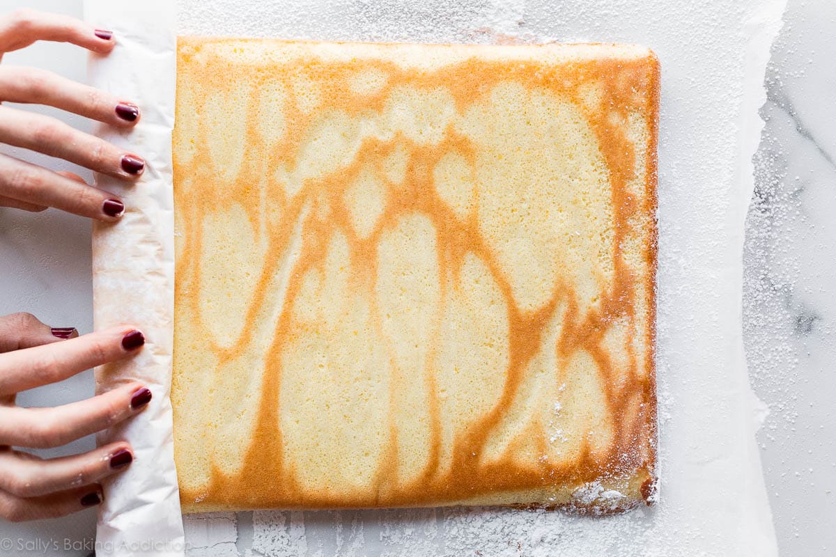 hands rolling sponge cake for champagne cake roll