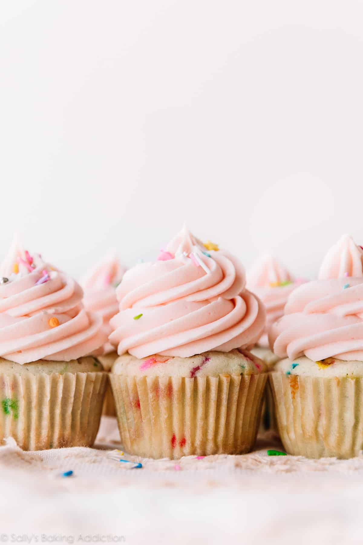 Cupcakes with sprinkles topped with pink buttercream
