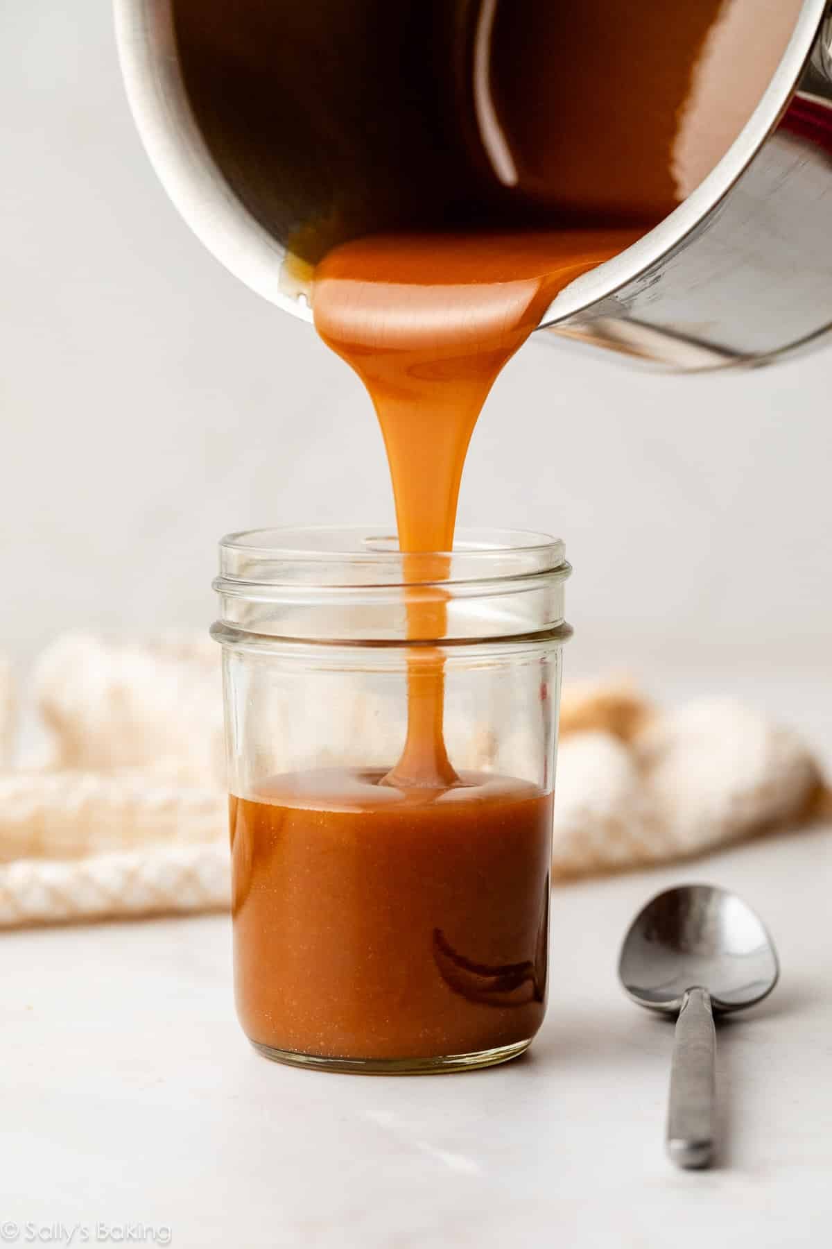 pouring salted caramel sauce into a glass jar.