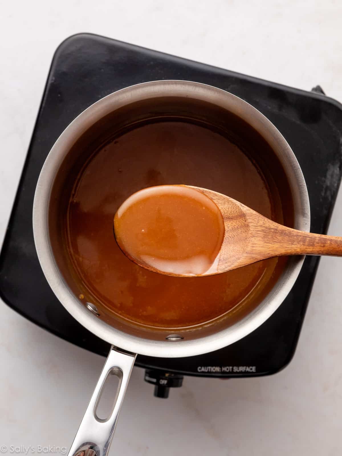 wooden spoon holding caramel sauce over a pot.