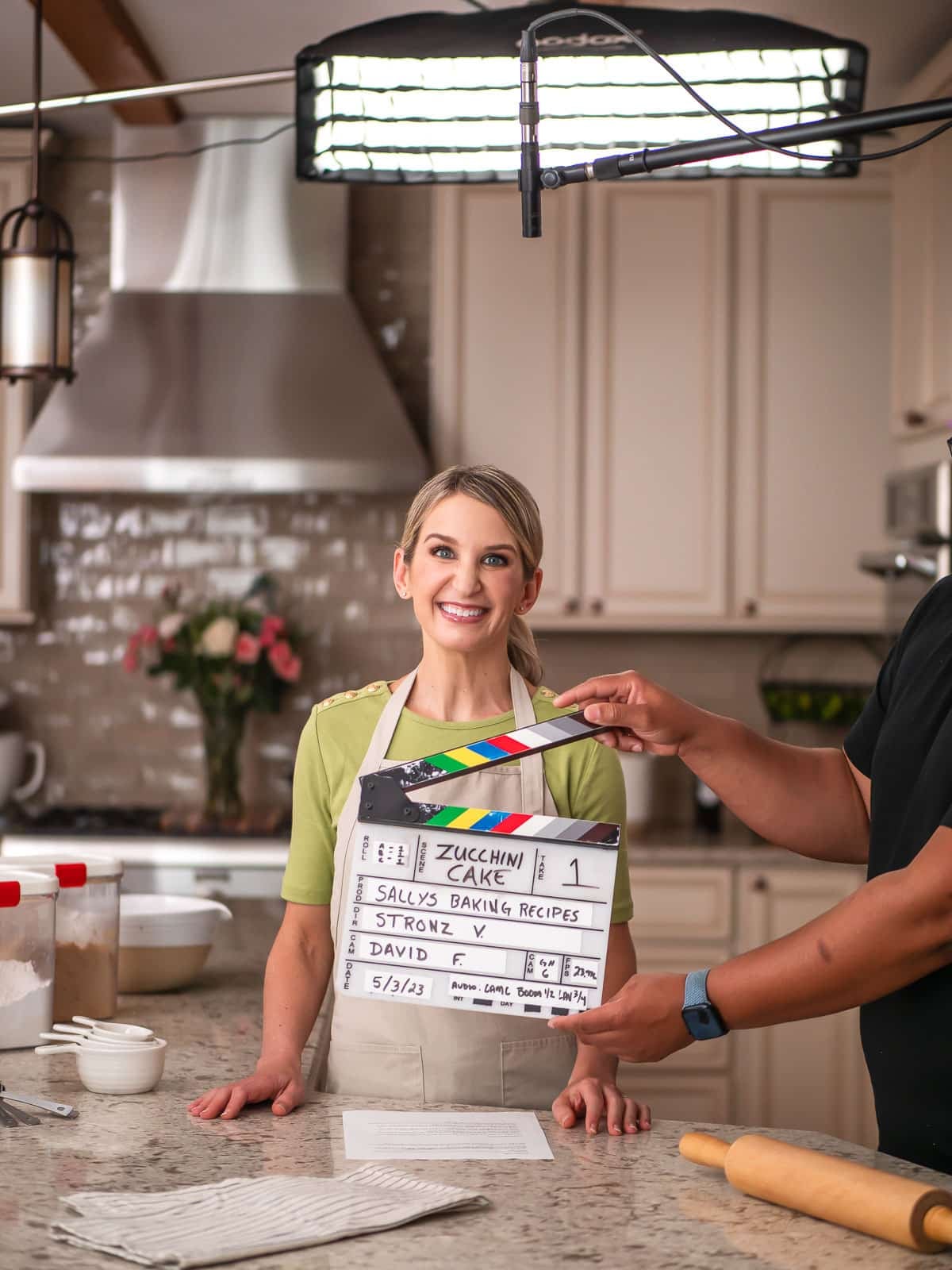 Sally wearing green shirt and khaki branded apron with videography marker in place.