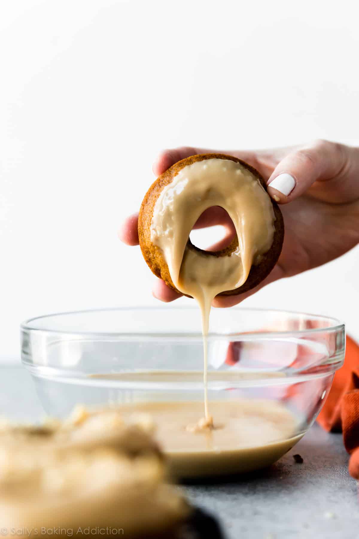 dipping pumpkin donut in brown sugar icing
