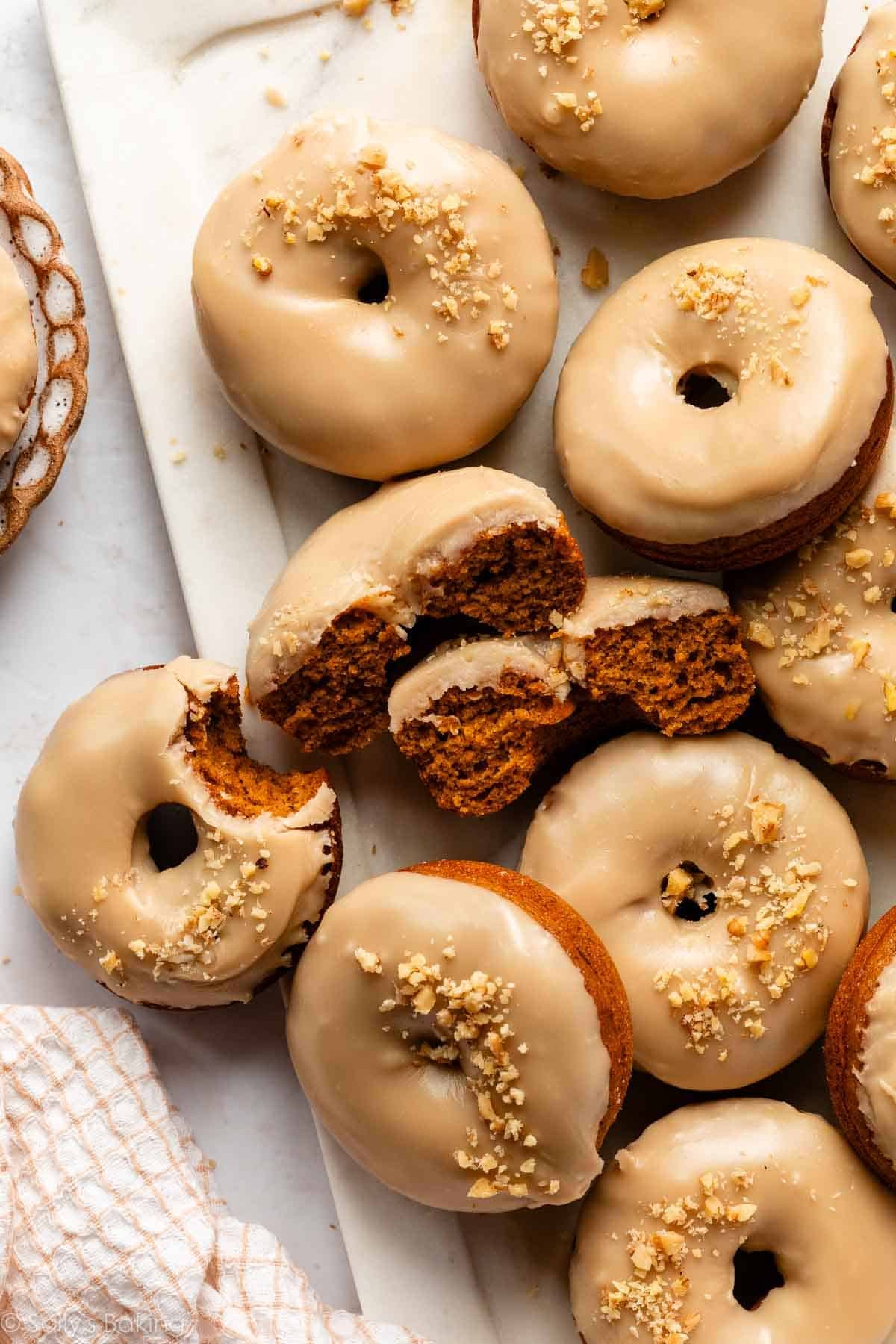 pumpkin donuts with brown sugar icing with crushed walnuts on top.