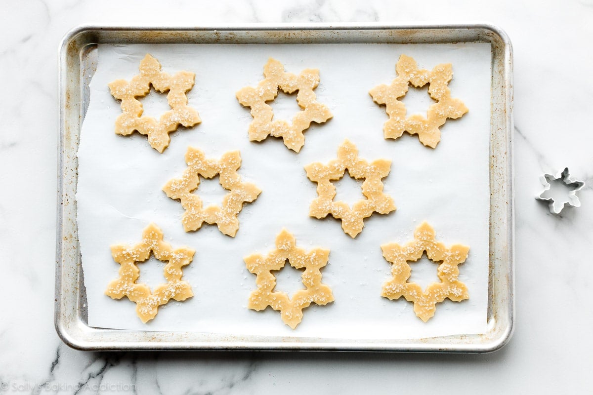 snowflake shaped sugar cookie dough on baking sheet