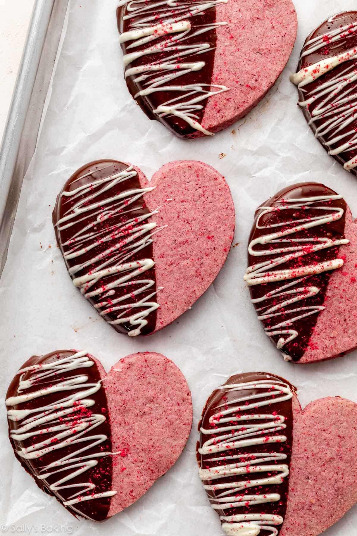heart-shaped raspberry Valentine's Day cookies dipped in chocolate and drizzled with white chocolate.
