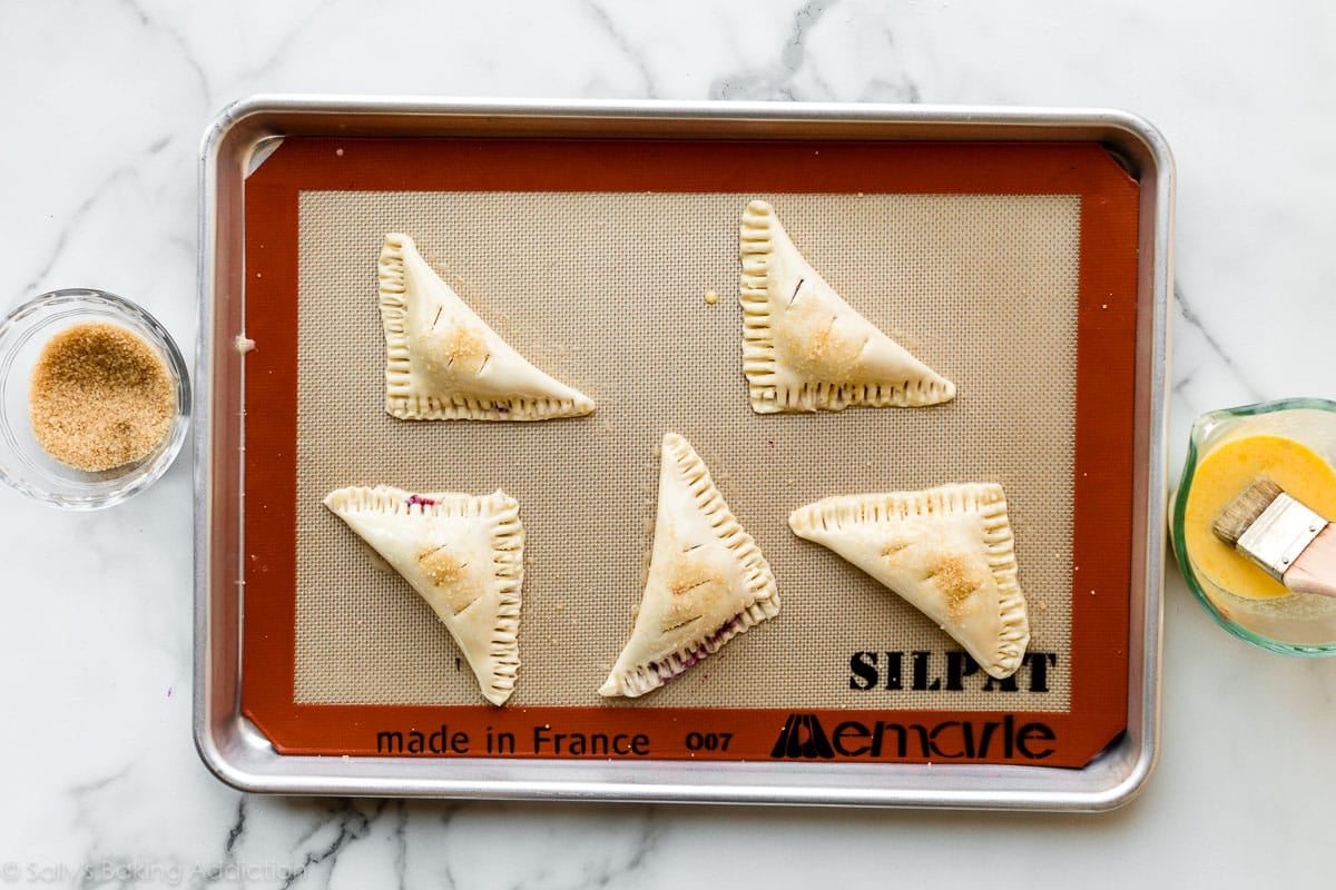 turnovers on baking sheet with egg wash on top before baking