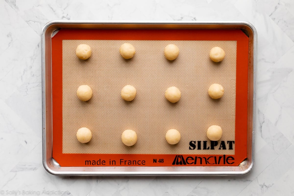 lemon coconut cookie dough balls on lined baking sheet