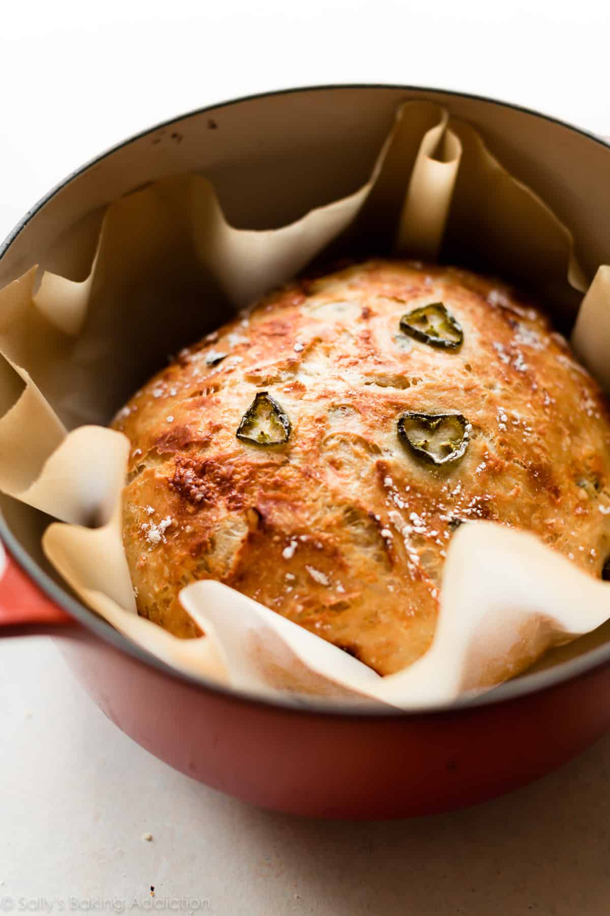 jalapeño cheddar bread with 3 jalapeños on top in dutch oven