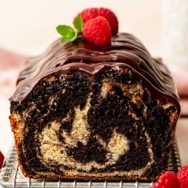 marble loaf cake with ganache and fresh raspberries on top.