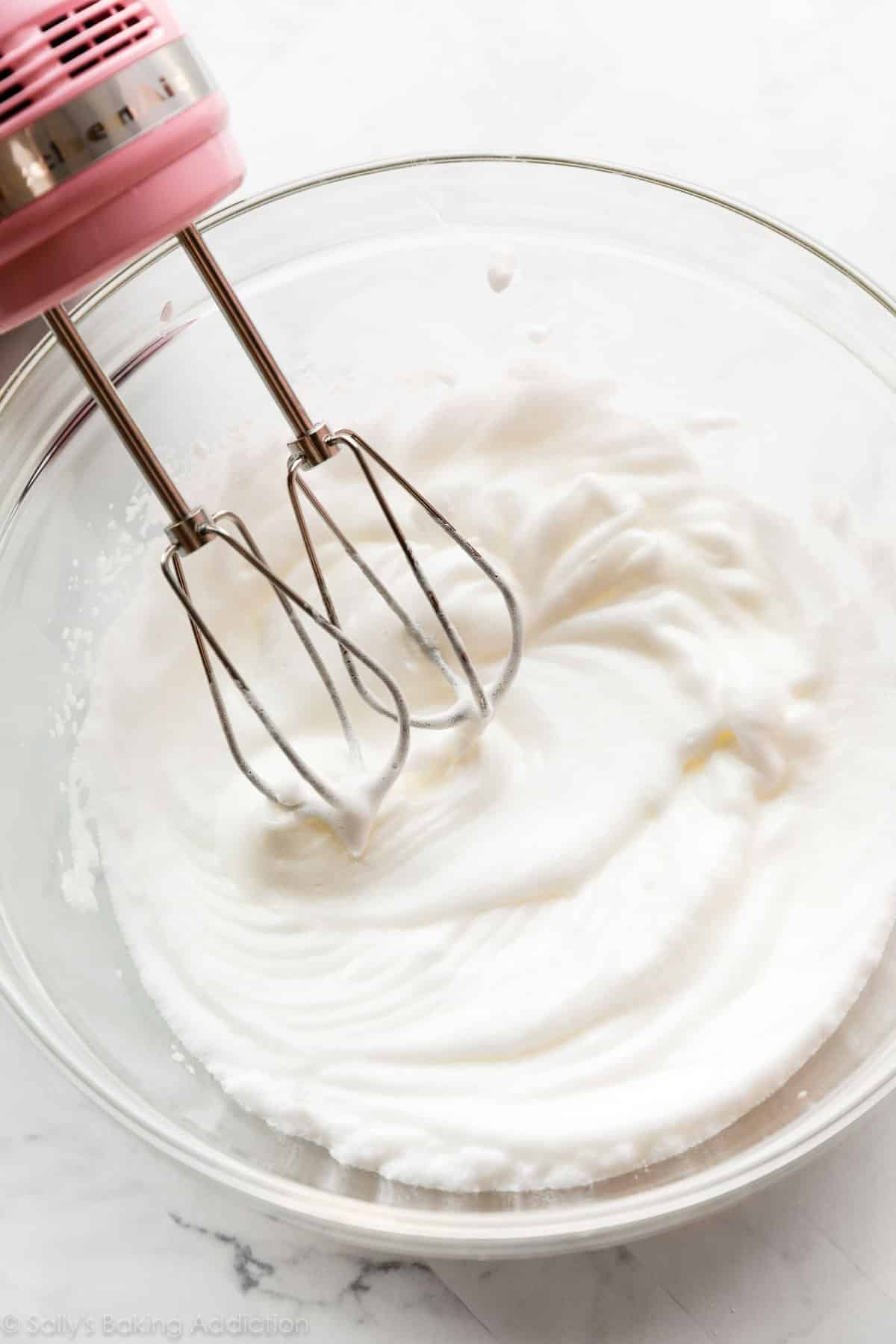 egg whites whipped into soft peaks shown in glass bowl