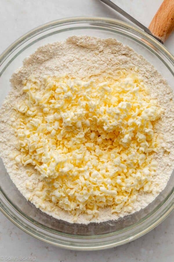 frozen grated butter on top of dry ingredients in large glass bowl.