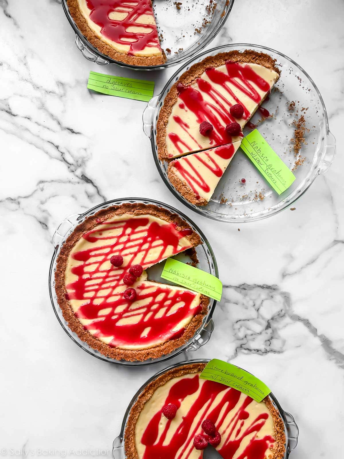 4 cheesecake pies with raspberry sauce drizzled on top.