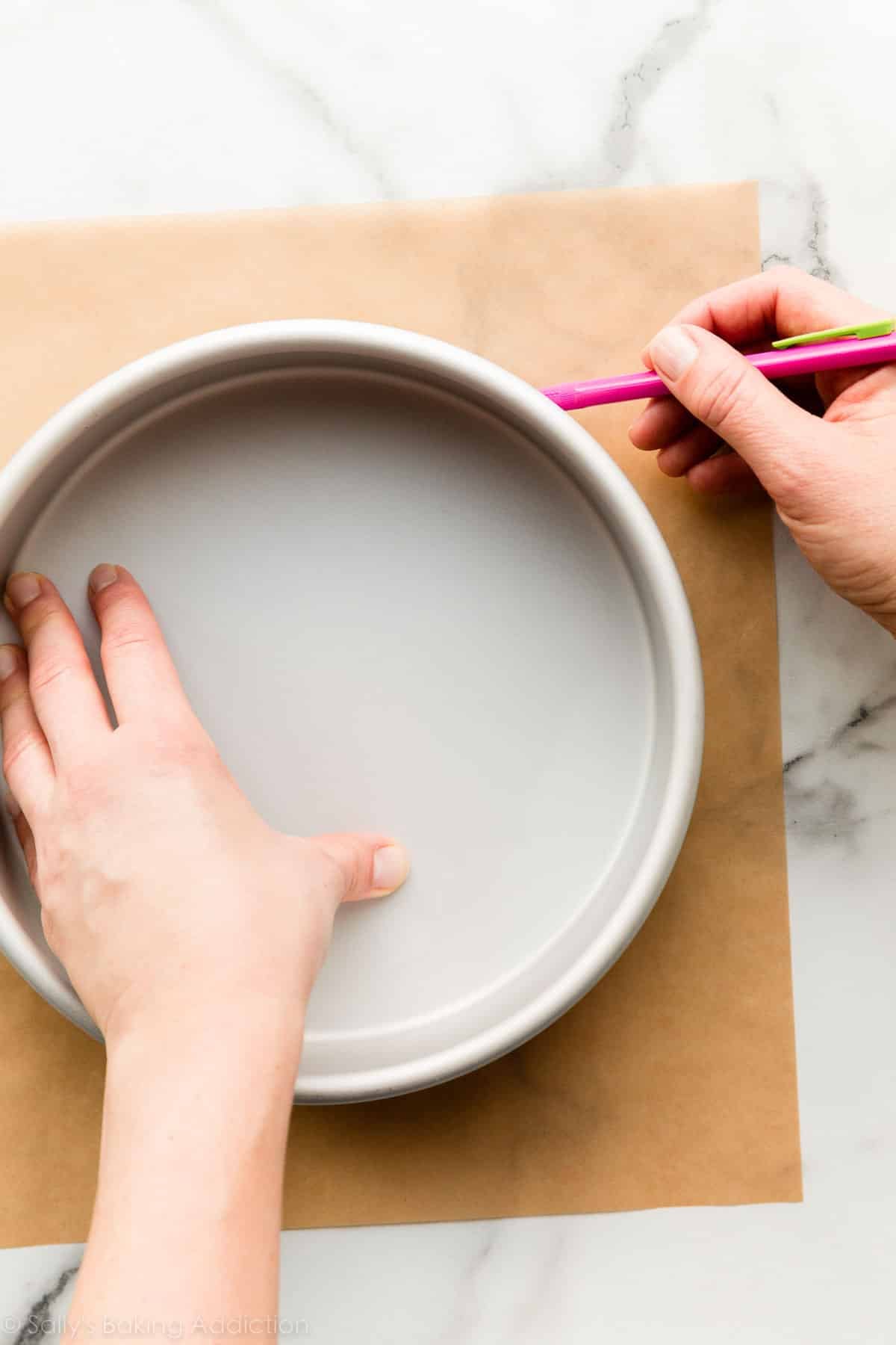tracing a round cake pan on brown parchment paper.