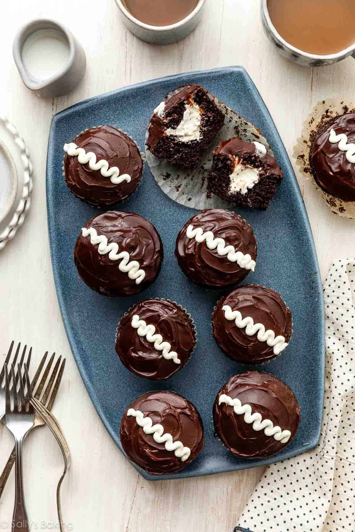 hostess cupcake copycat cream-filled cupcakes on blue platter with mugs of coffee around it.