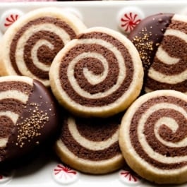 pinwheel cookies on white plate with peppermint swirls sitting on red linen.