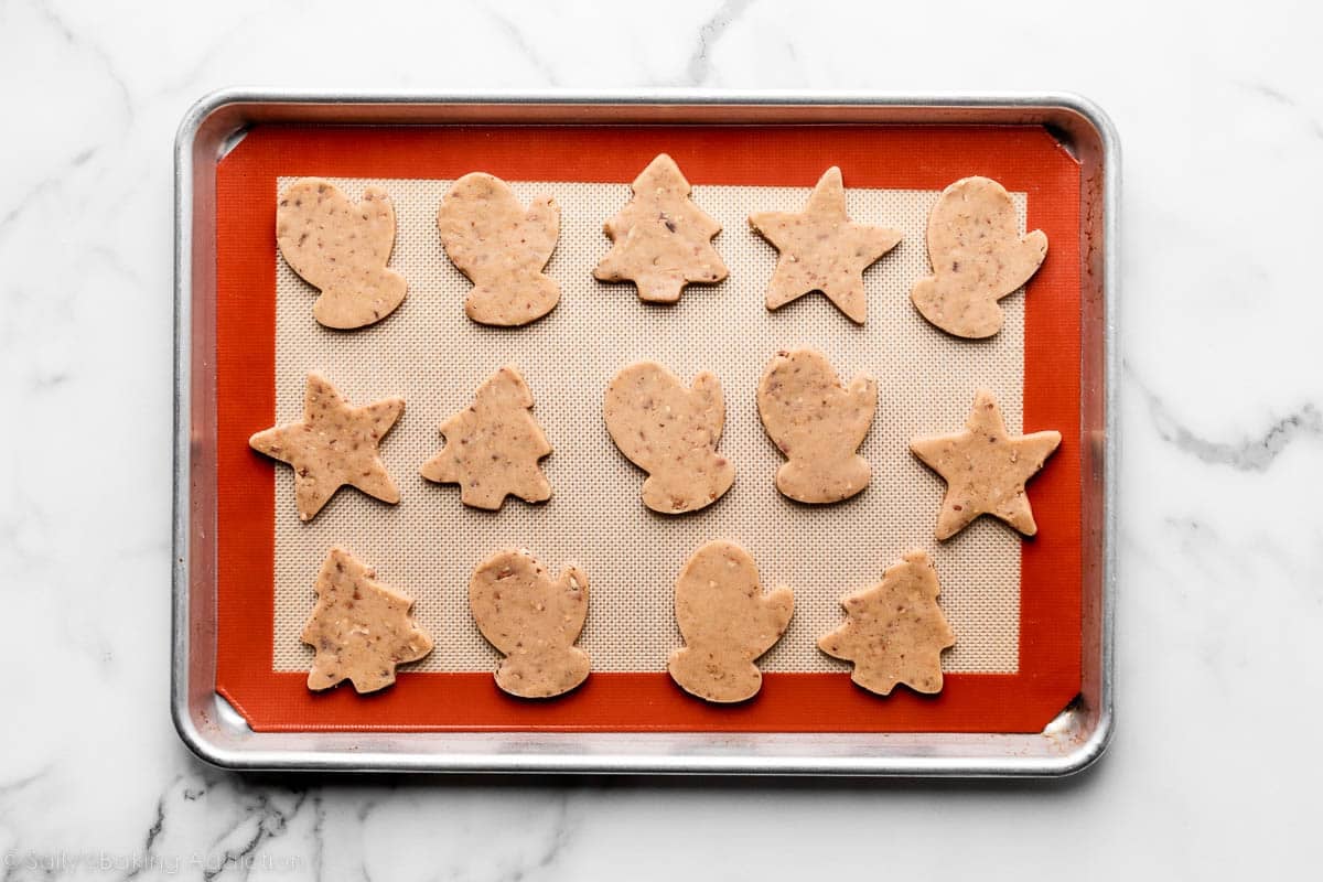 brown sugar pecan cookies cut into Christmas shapes and arranged on silicone baking mat-lined baking sheet.