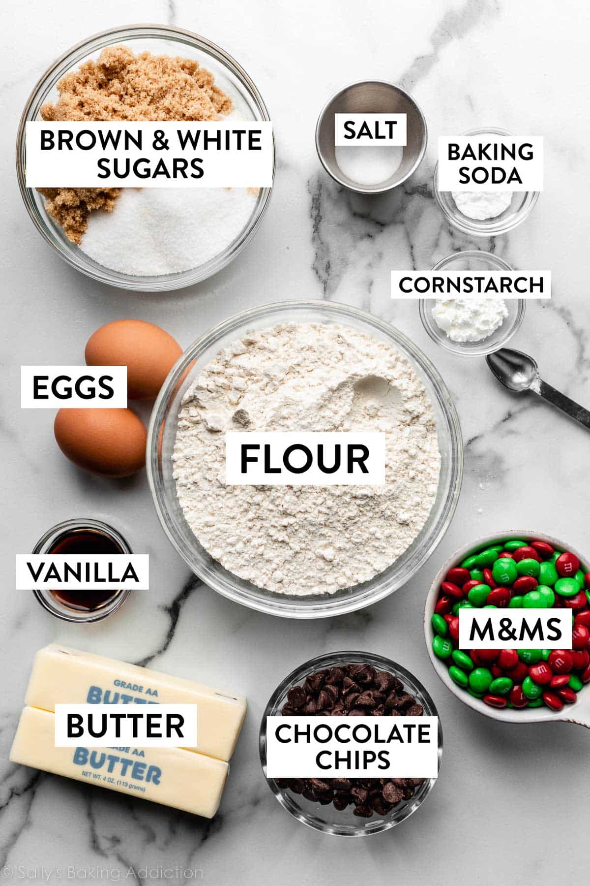 ingredients on marble counter including flour, eggs, brown and white sugars, butter, and more.