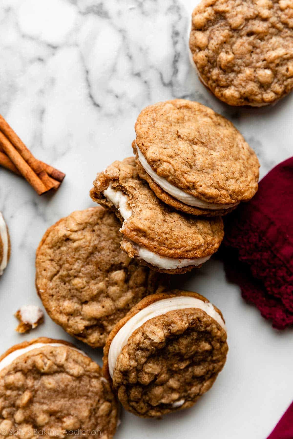 oatmeal cream pies with eggnog buttercream arranged on marble counter with a cinnamon stick for decor.