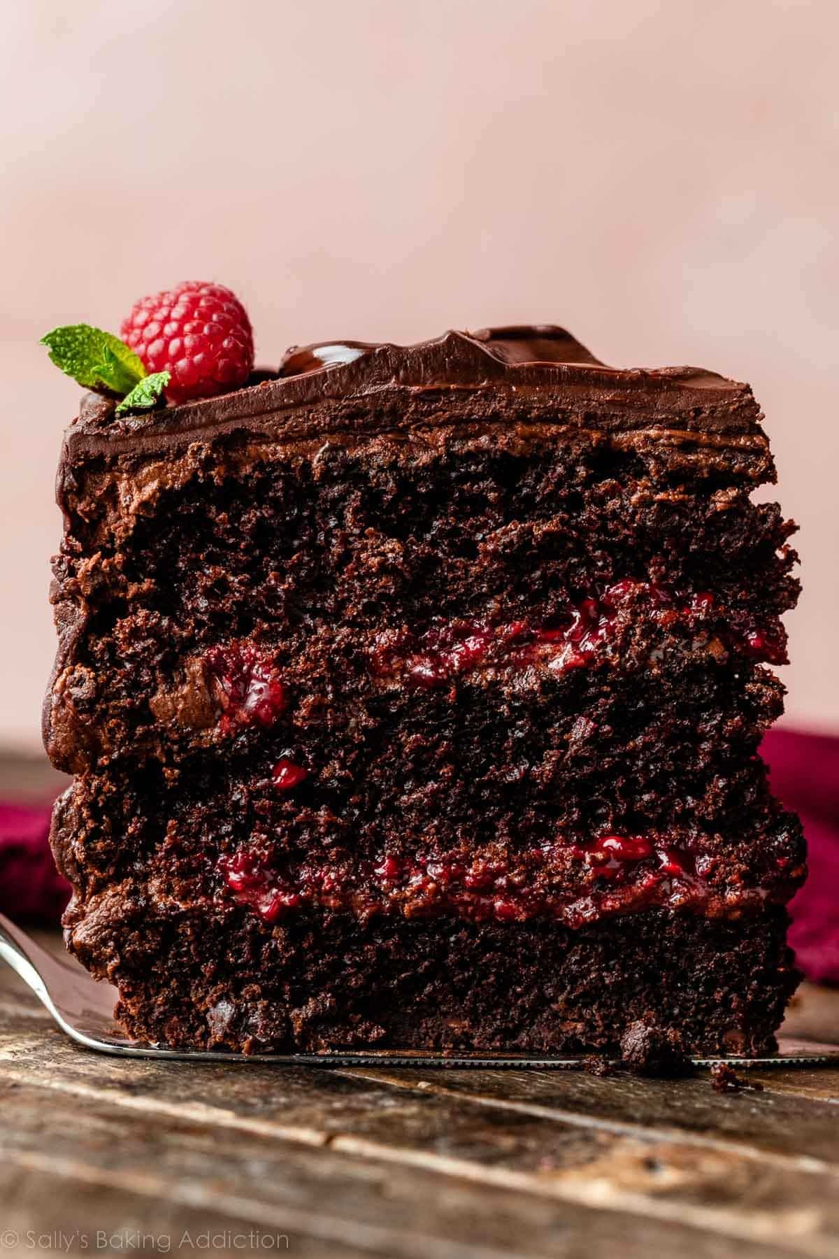 slice of 3-layer chocolate raspberry cake with chocolate raspberry ganache and raspberry filling.