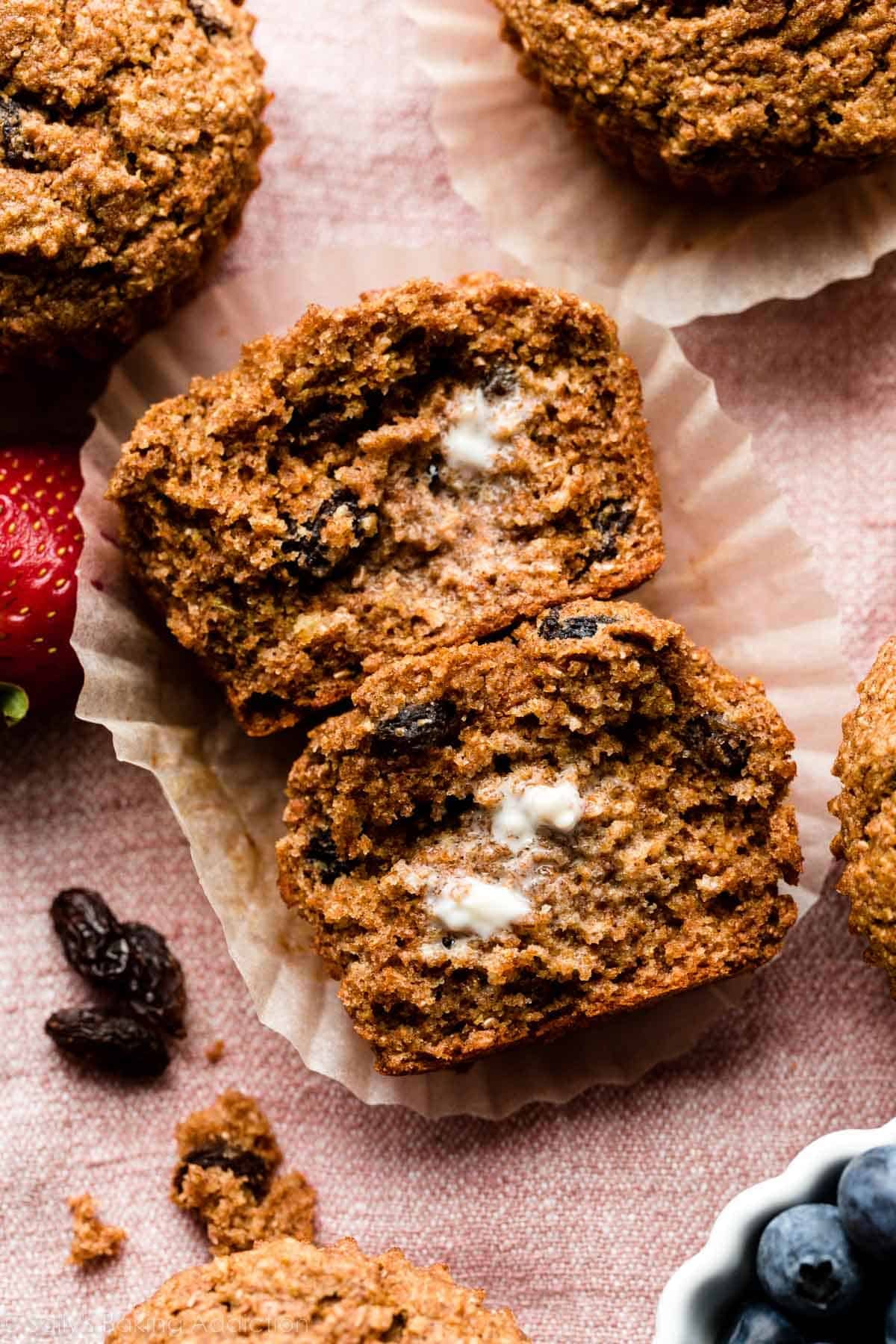 bran muffin cut in half with melted butter on top on pink linen.