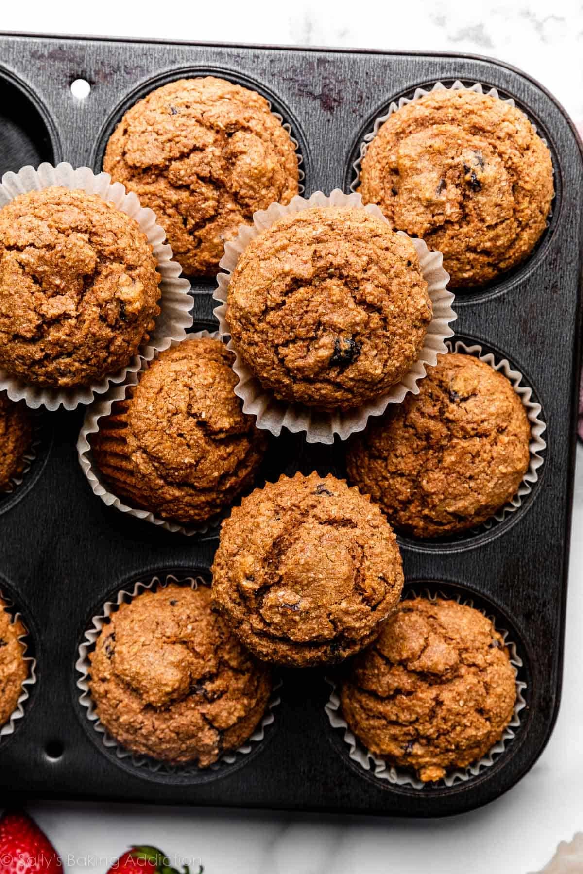 overhead photo of bran muffins in and on top of dark metal muffin pan.