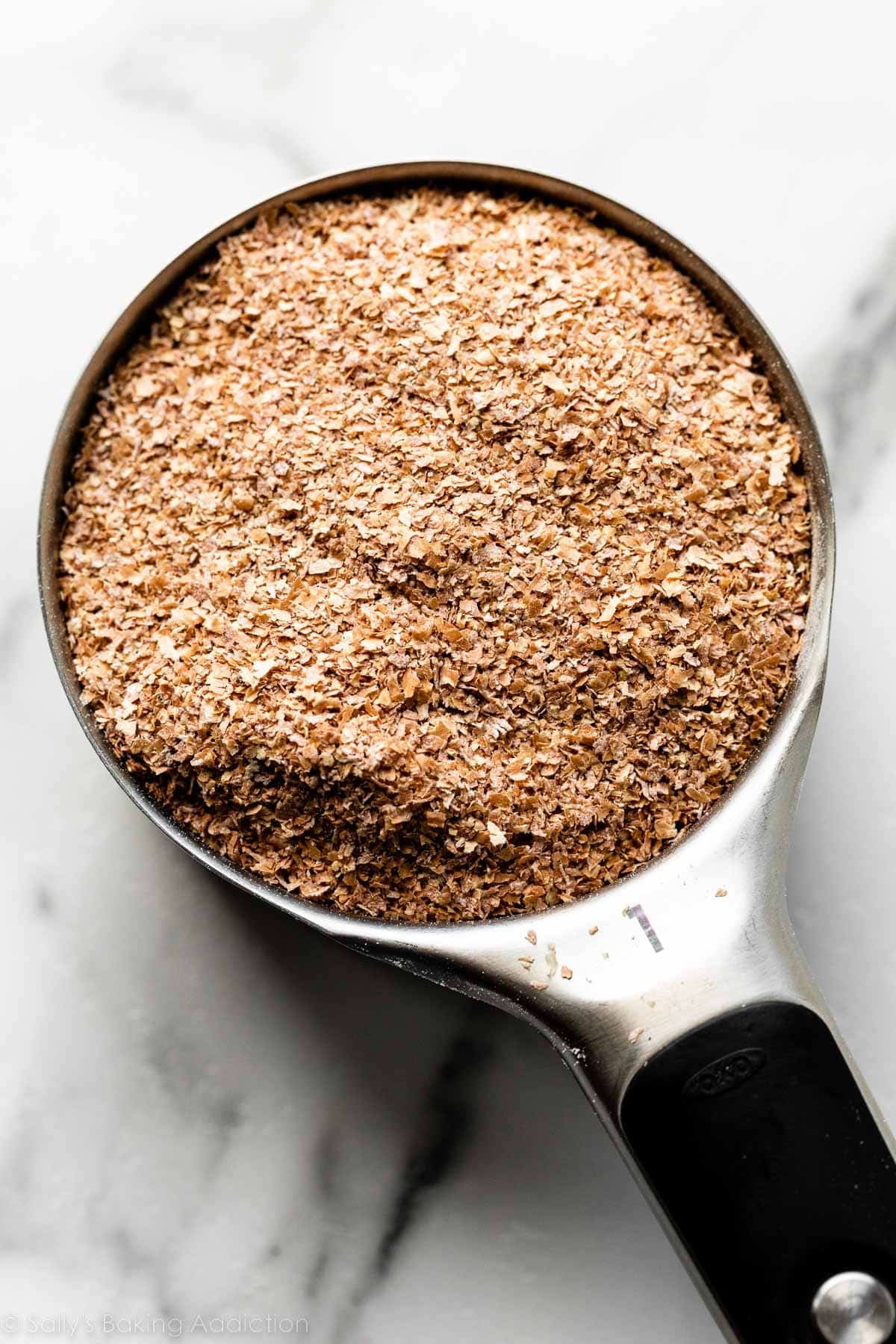 close-up photo of measuring cup filled with wheat bran.