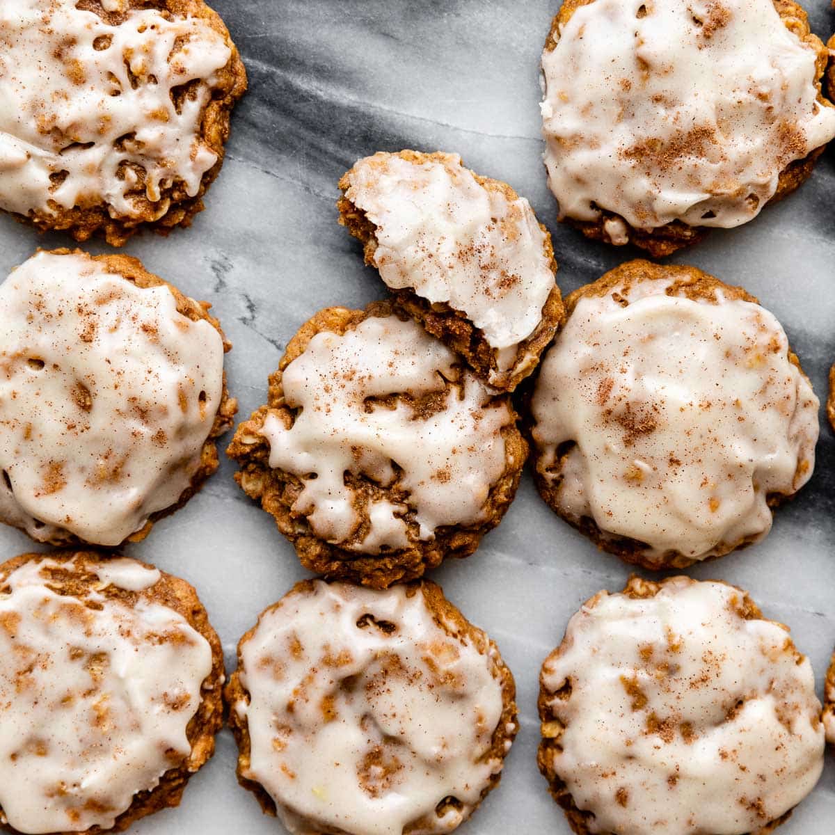 brown butter pumpkin oatmeal cookies with icing on top on marble countertop.