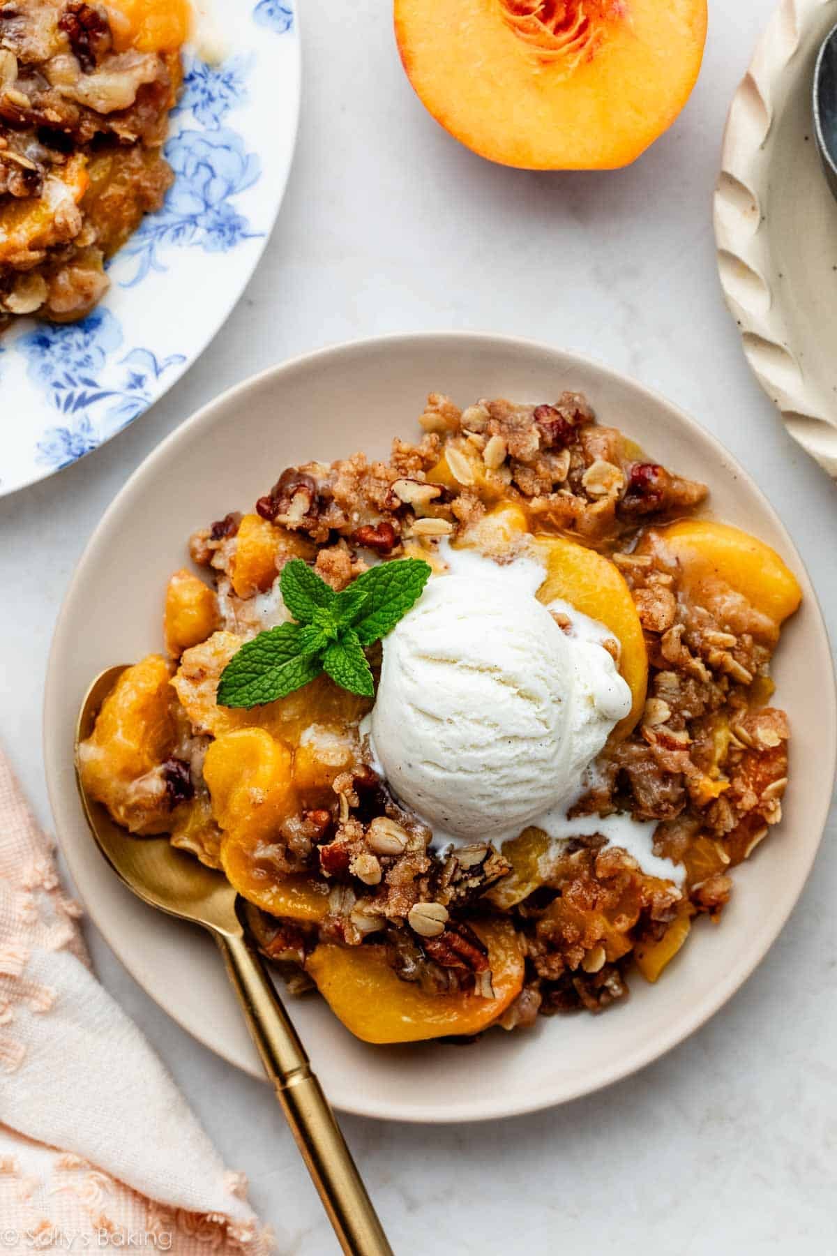 peach crisp with vanilla ice cream on beige plate.