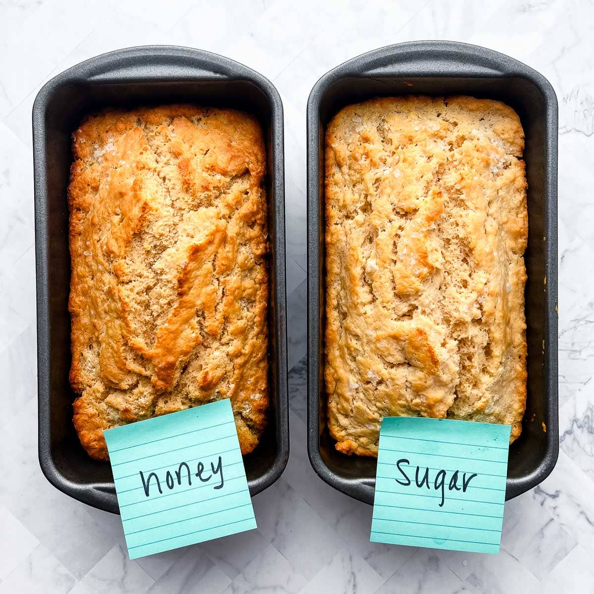 bread loaves in loaf pans with blue post-its at one end of pan.